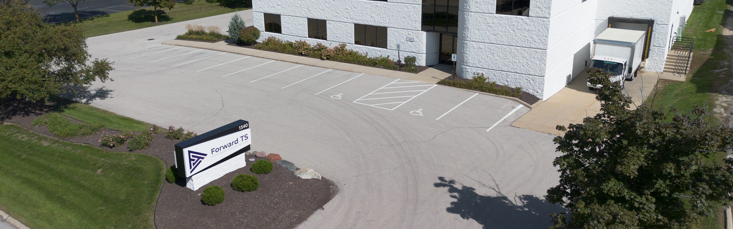 Aerial view of the Forward TS office at 1540, showing the company sign, parking lot and building exterior on a sunny day.